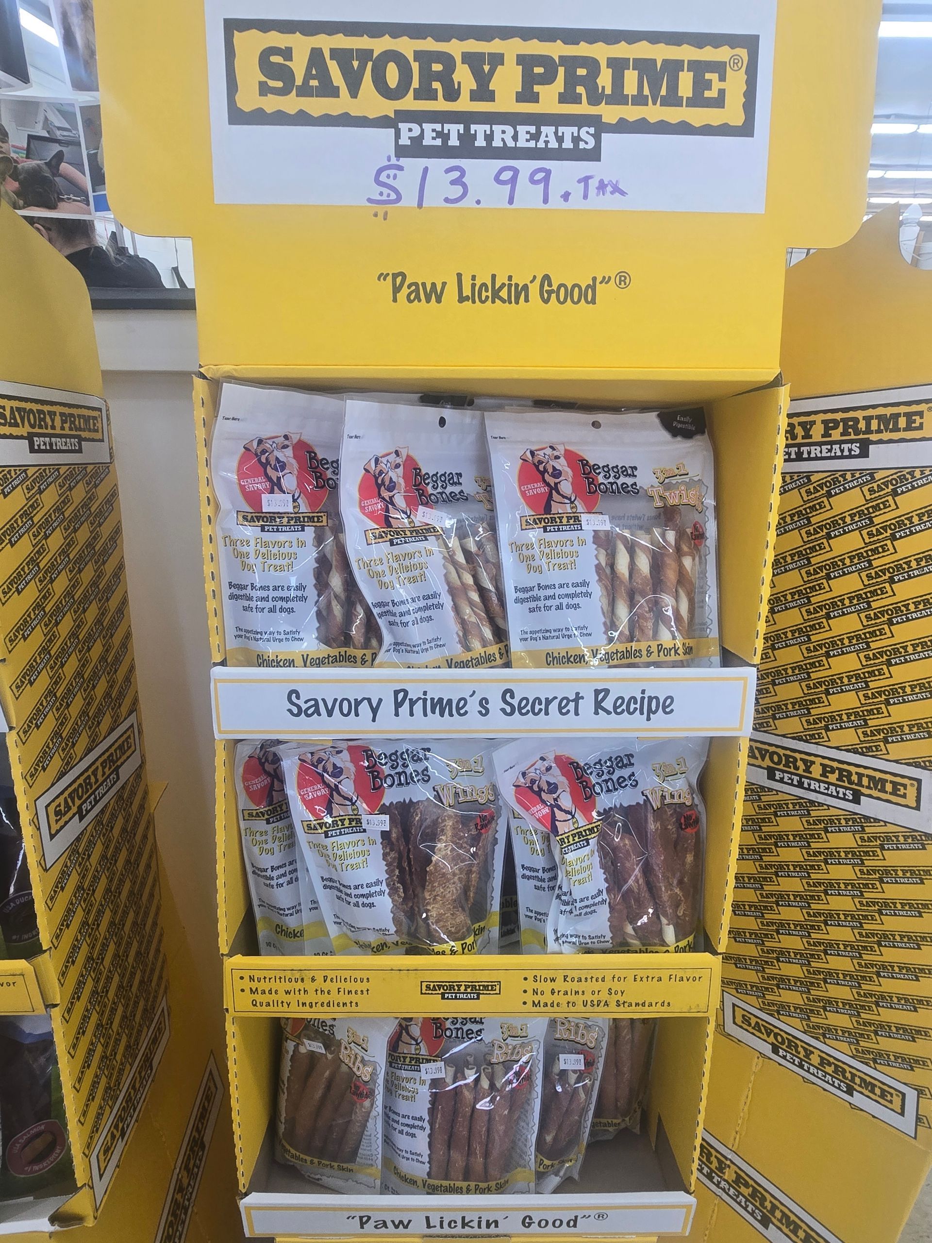 A bright yellow retail display stand filled with bags of Savory Prime pet treats, priced at $13.99 each.
