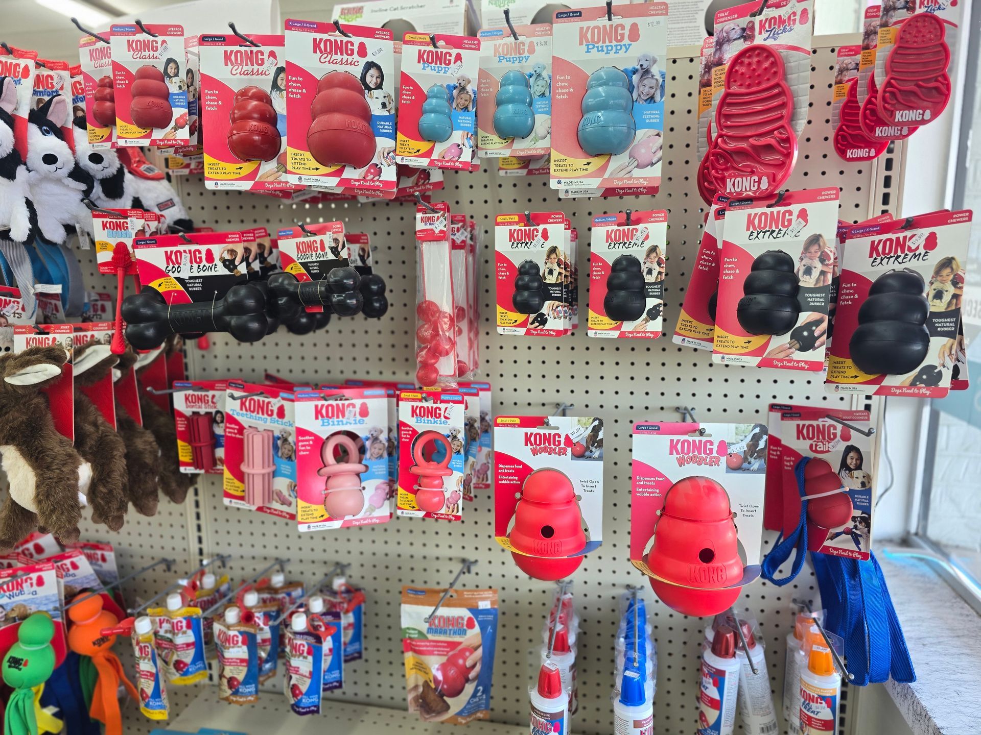 A store shelf displays a variety of KONG dog toys in red, blue, and black