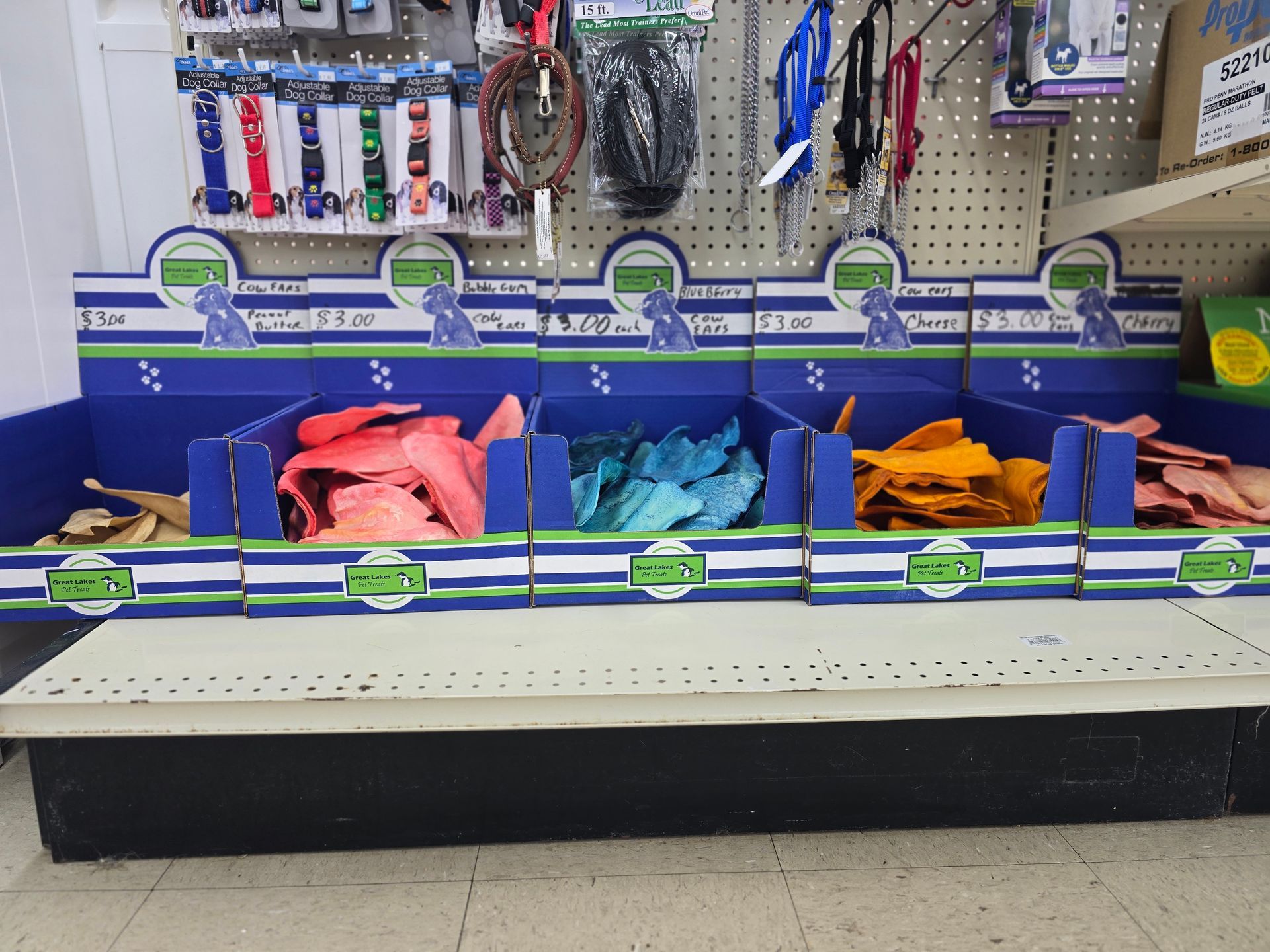 A retail store shelf featuring five bins filled with colorful dog collars, with more packaged collars hanging above.