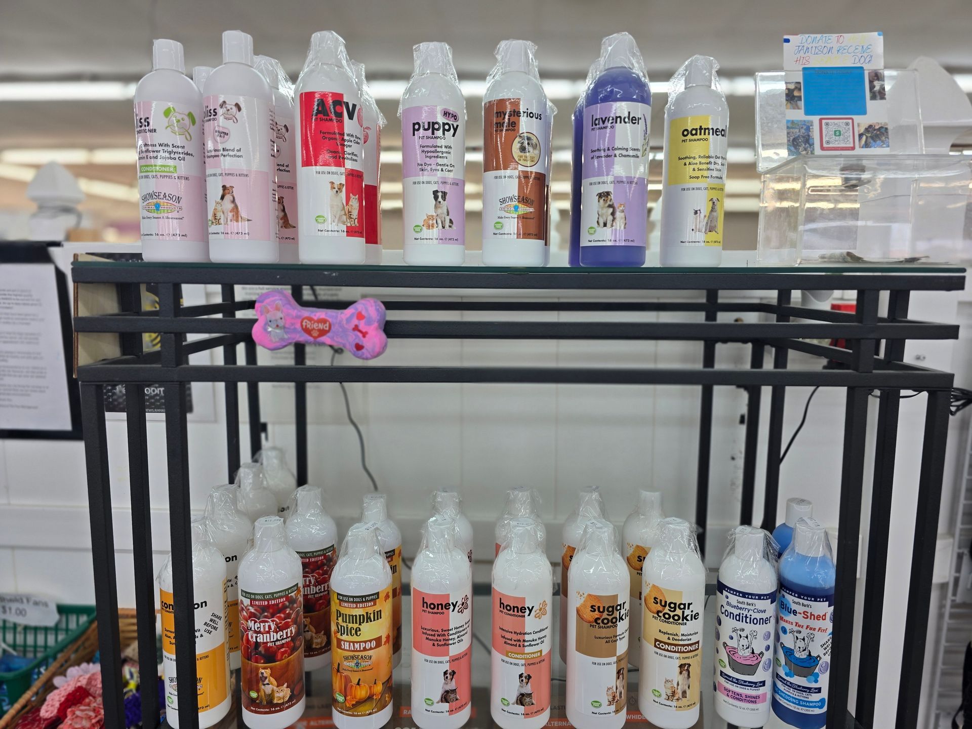 A black metal shelf holds various bottles of colorful pet shampoo with illustrated labels in a retail setting.