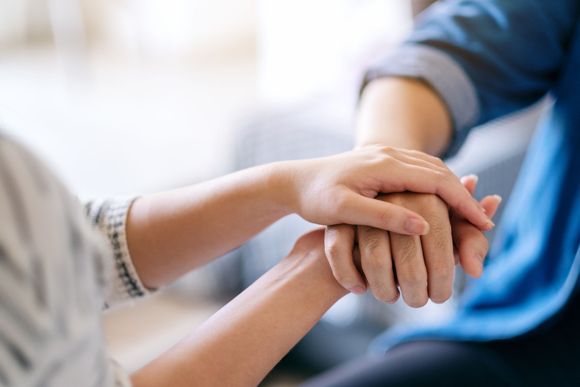 Two hands clasped together, providing comfort and support.