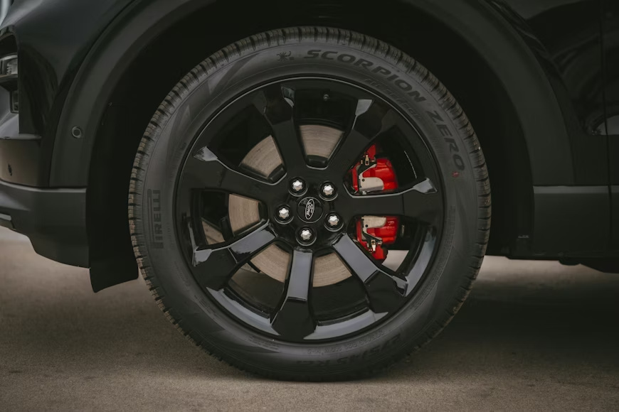 Black car wheel with black rim, red brake calipers, and Pirelli Scorpion Zero tire.
