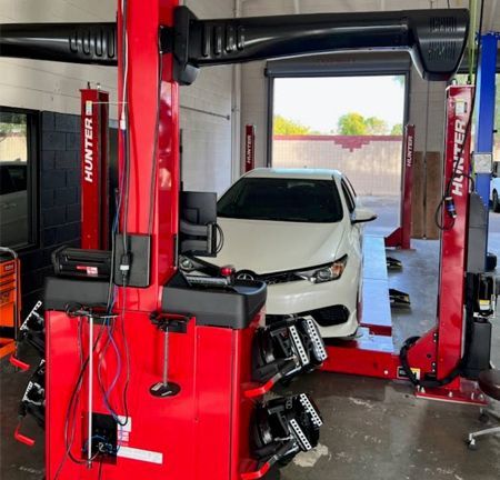White car on a red Hunter wheel alignment machine in a garage.