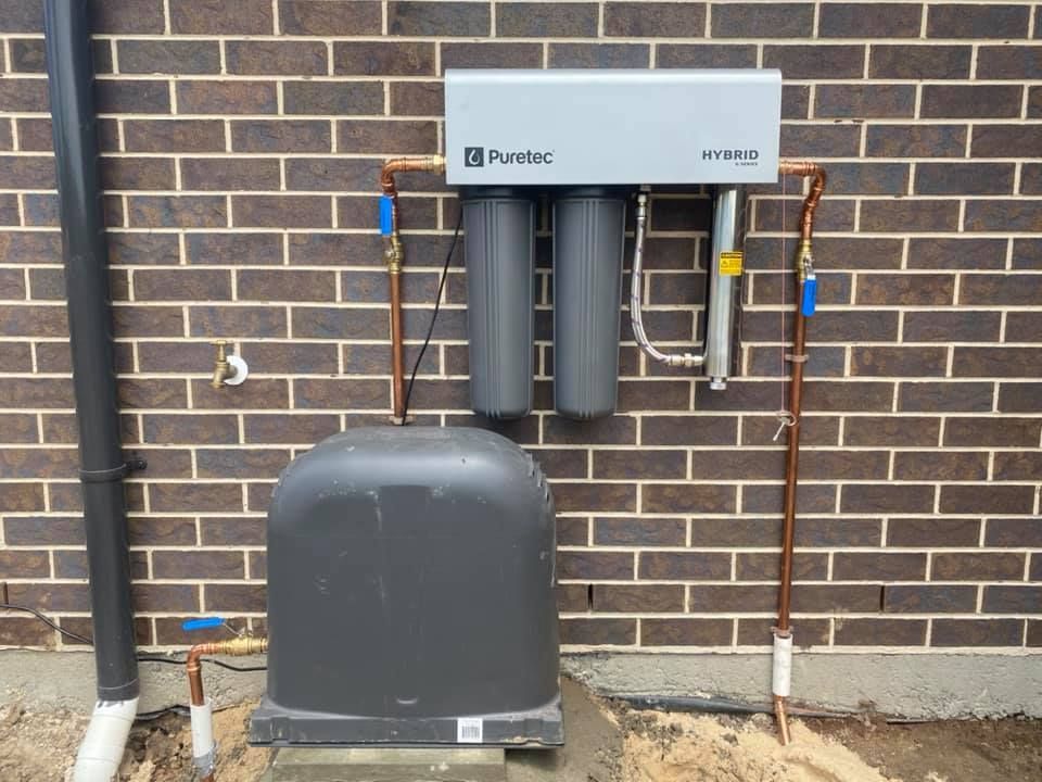 Exterior Pump Unit and Piping Mounted on a Wall Beside a Large Tank — Medowie Plumbing & Gas in in Newcastle