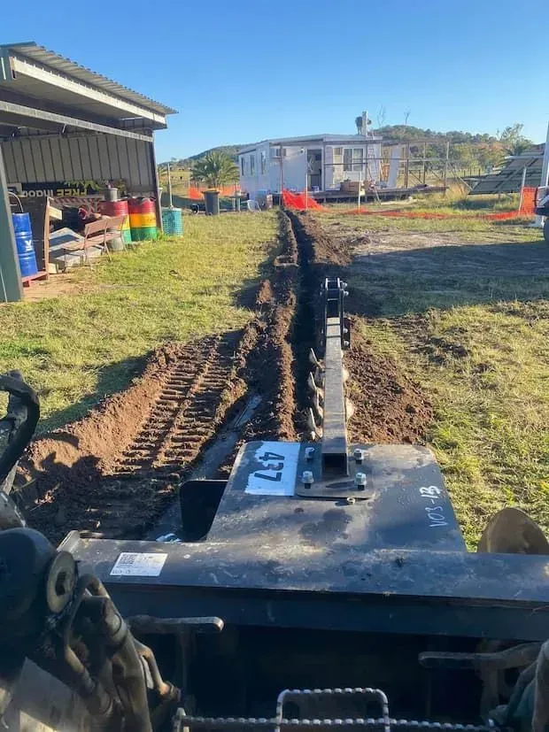 A Person Is Driving a Bulldozer on A Dirt Road — Medowie Plumbing & Gas In Medowie, NSW