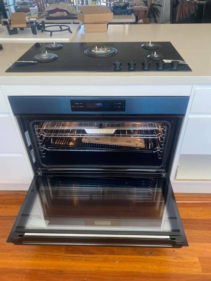 Open Oven Beneath a Black Glass Cooktop — Medowie Plumbing & Gas in in Maitland