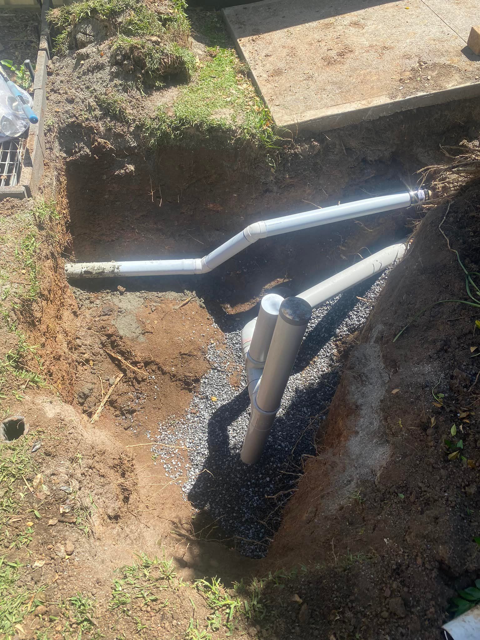 Pipes Buried in A Gravel-Lined Trench Near a Concrete Structure — Medowie Plumbing & Gas in in Maitland