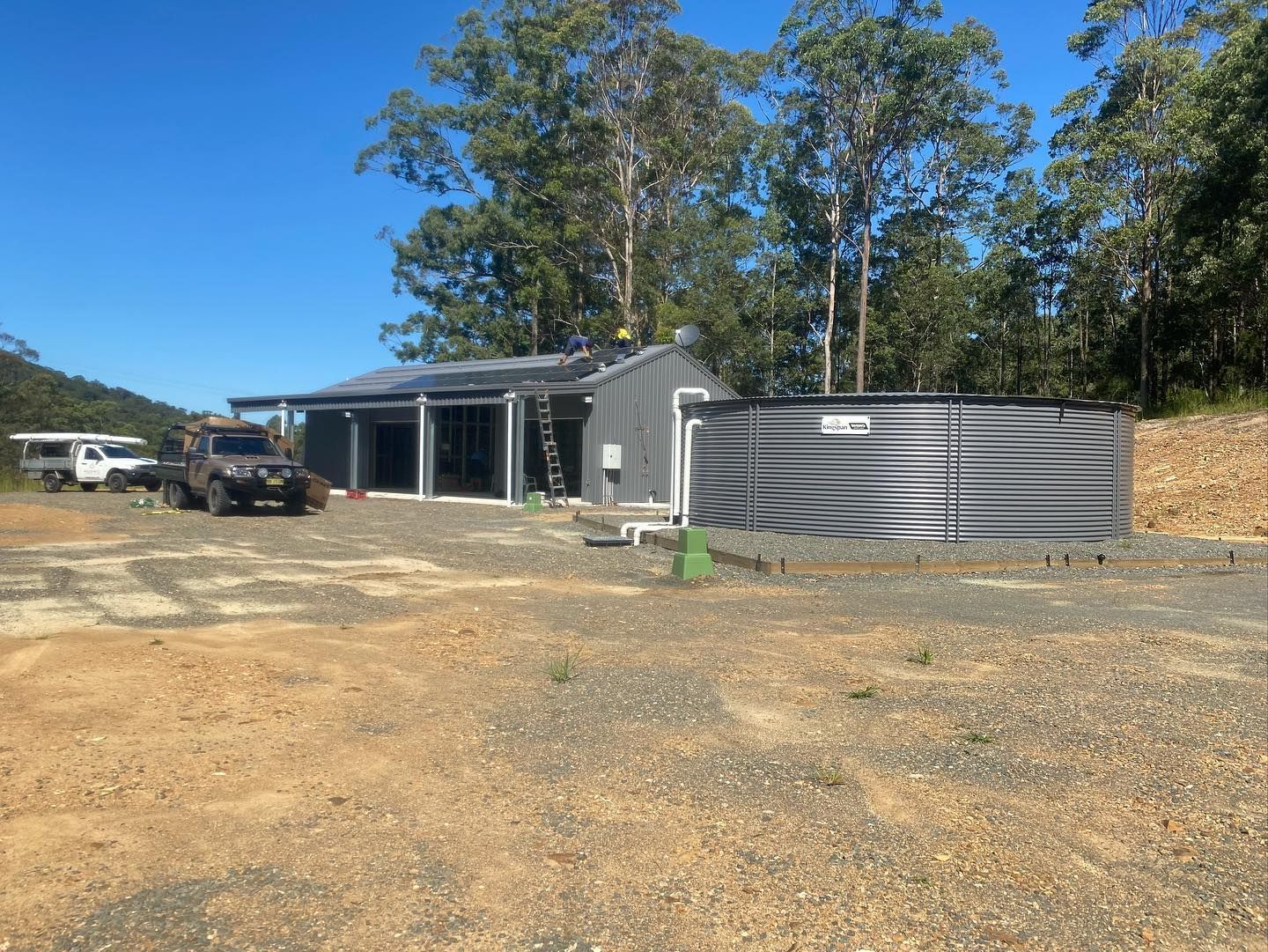 Rural Metal Building With a Corrugated Tank and Gravel Yard — Medowie Plumbing & Gas In Medowie, NSW