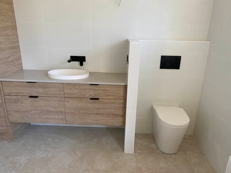 Bathroom With Wood Vanity, Vessel Sink, and Wall-mounted Toilet — Medowie Plumbing & Gas in in Maitland