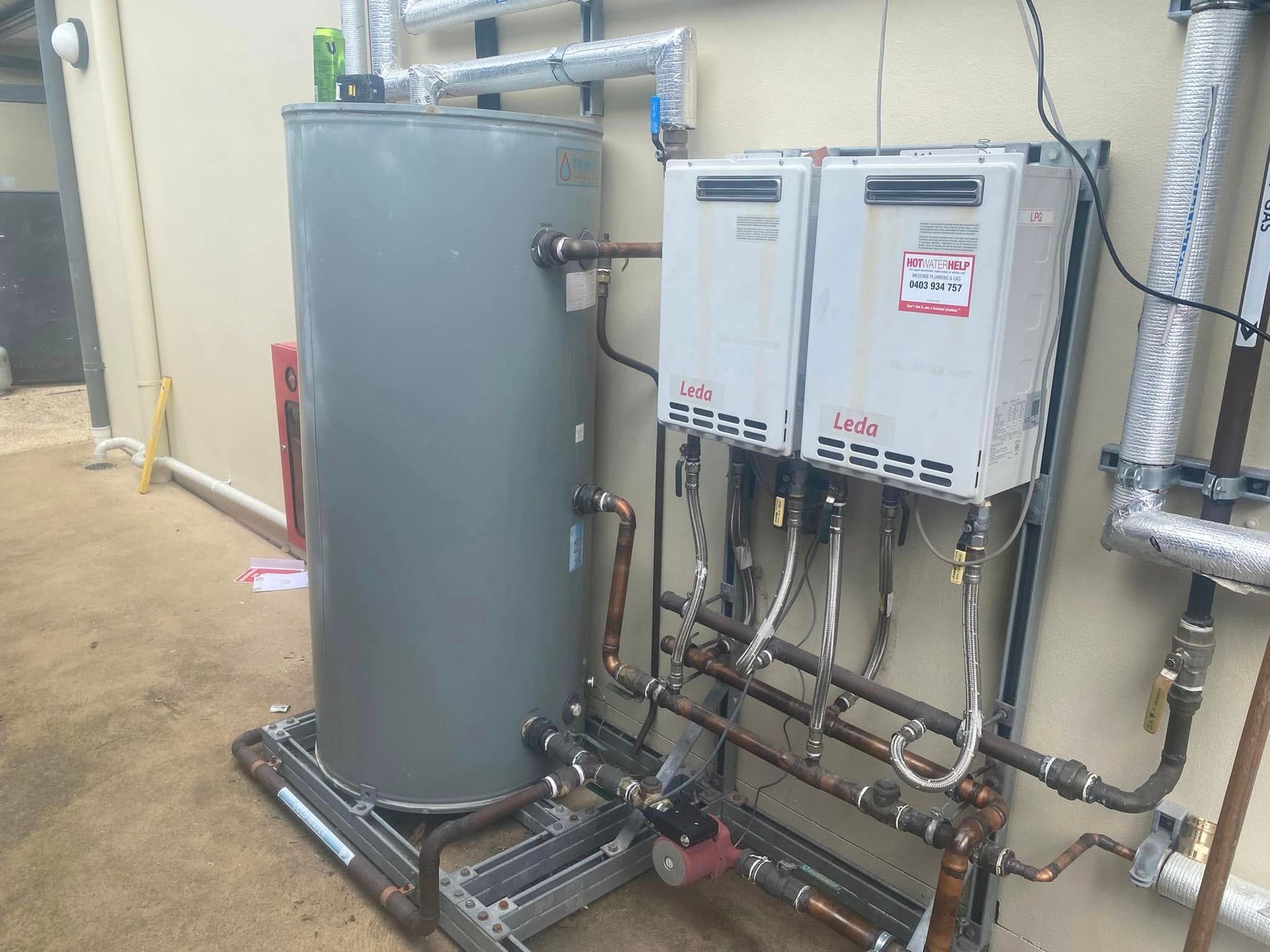 Utility room with gray tank, white wall-mounted units, and exposed pipes and — Medowie Plumbing & Gas In Medowie, NSW