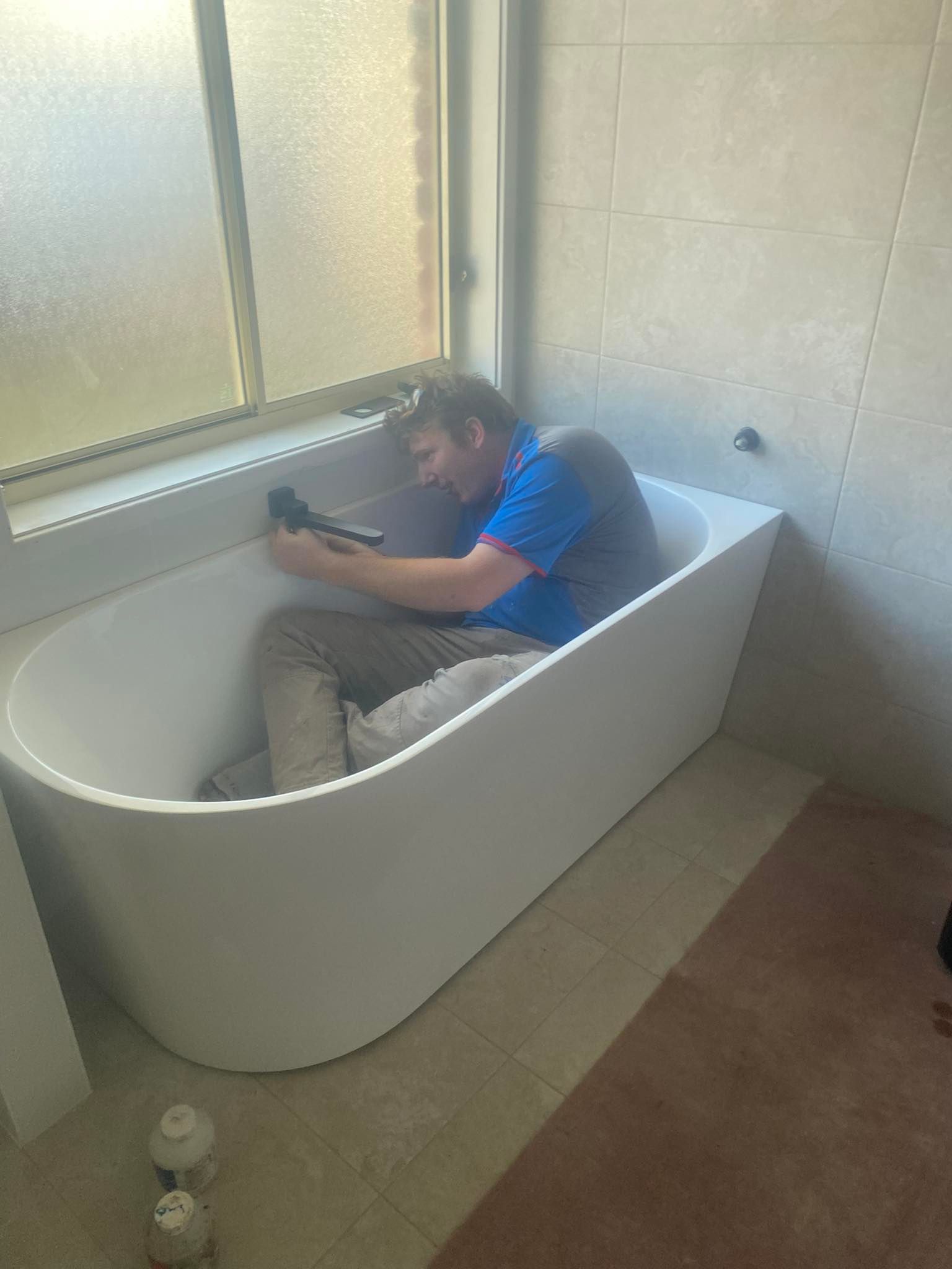 Person Sitting Curled Up in a White Bathtub — Medowie Plumbing & Gas in in Maitland