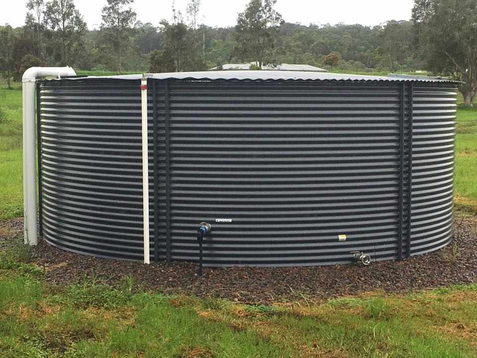 Dark Corrugated Metal Water Tank in A Grassy Field — Medowie Plumbing & Gas in in Maitland