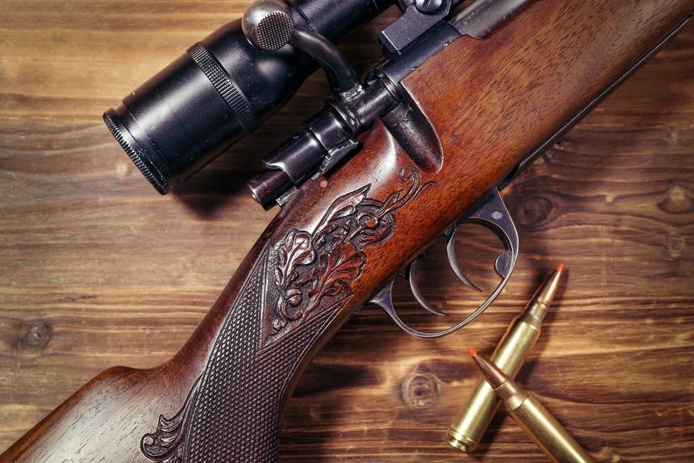 A Rifle With a Scope Rests on a Wooden Table — Coffs Coast Firearms In Coffs Harbour, NSW