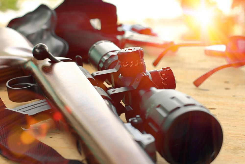 A Wooden Table Displays a Rifle Equipped With a Scope — Coffs Coast Firearms In Coffs Harbour, NSW