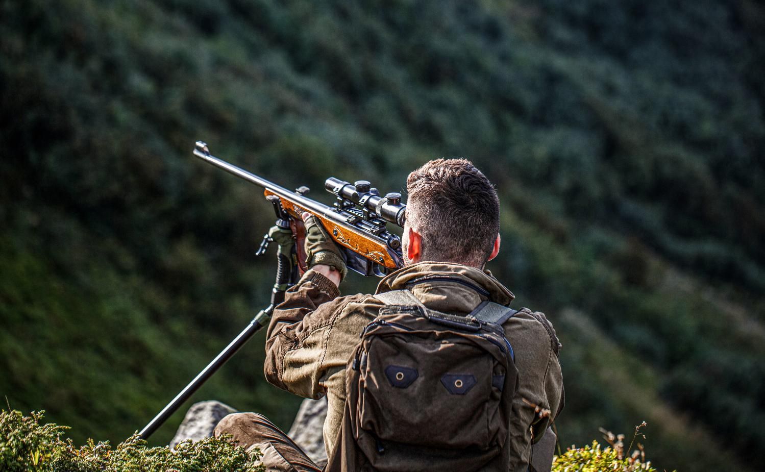 A Man Sits on a Grassy Hill, Holding a Rifle — Coffs Coast Firearms In Lismore, NSW