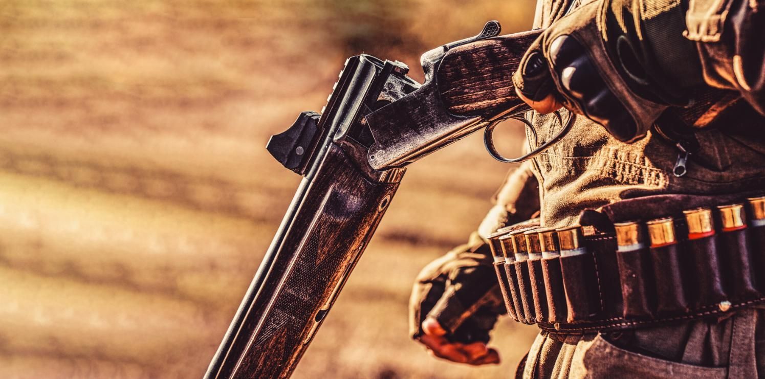 In a Field, a Man Grips a Gun and a Rifle — Coffs Coast Firearms In Coffs Harbour, NSW