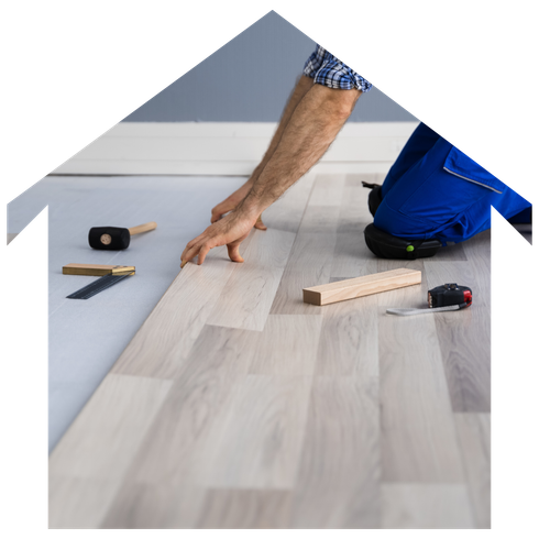A man is installing a wooden floor in the shape of a house
