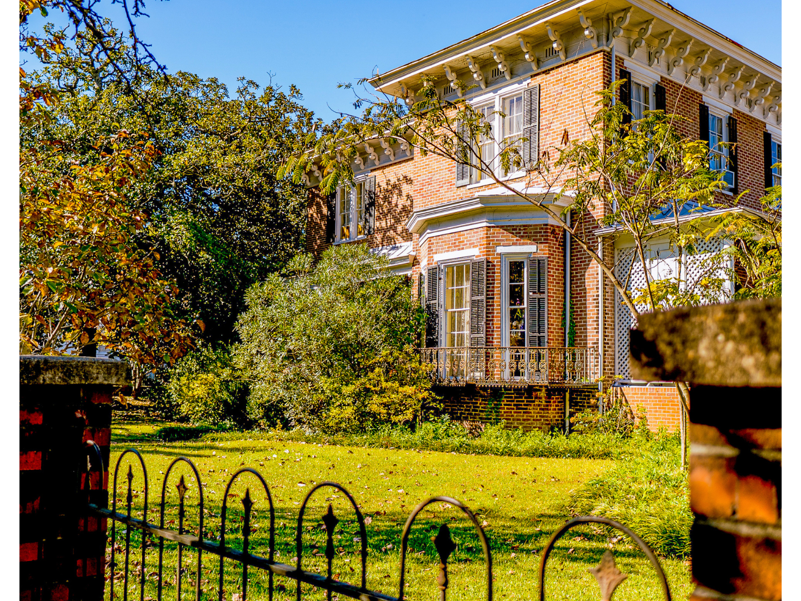 A large brick house with a wrought iron fence in front of it