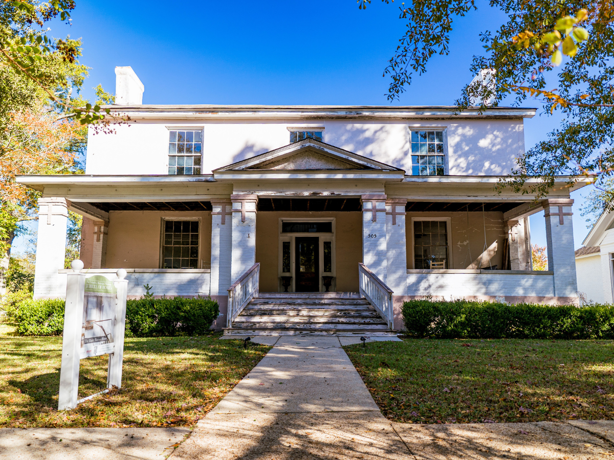 A large white house with a large porch and stairs is for sale.
