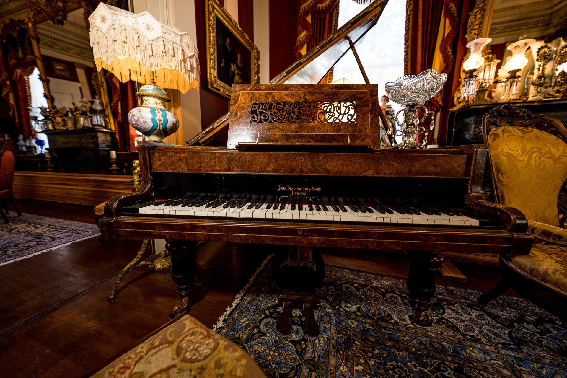 An antique grand piano is sitting in a living room.