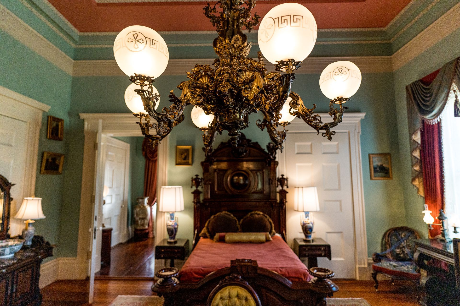 A bedroom with a bed lamps and a chandelier hanging from the ceiling