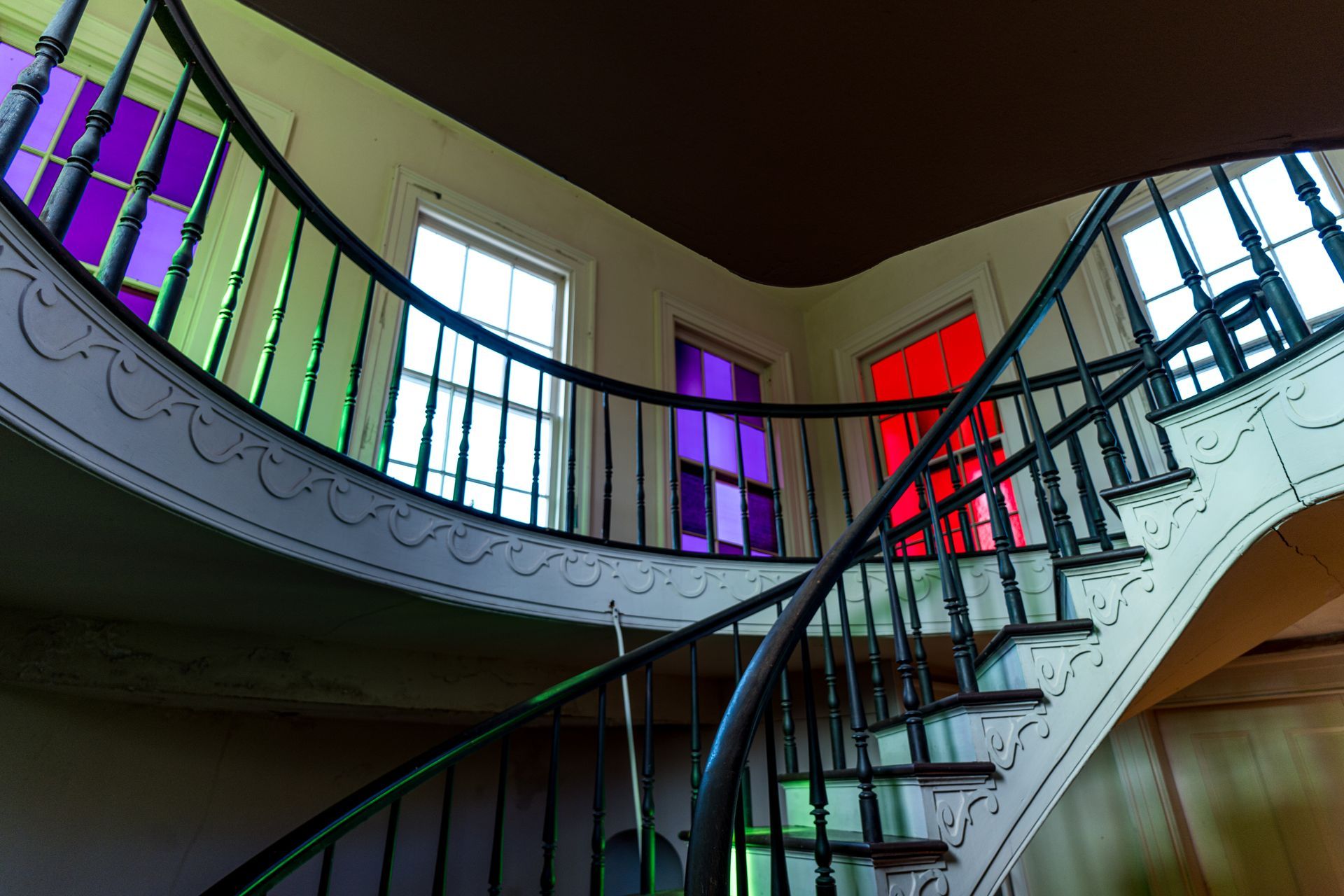 A spiral staircase with stained glass windows on the railing