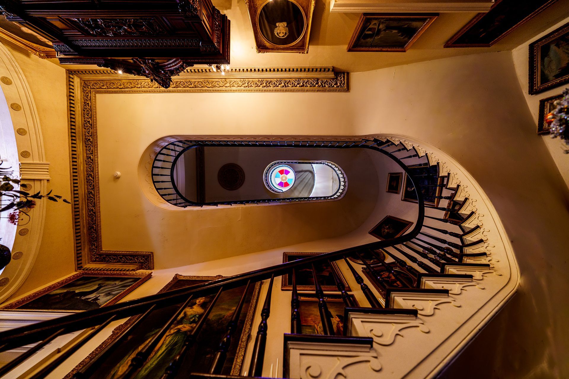 Looking up at a spiral staircase with a stained glass window