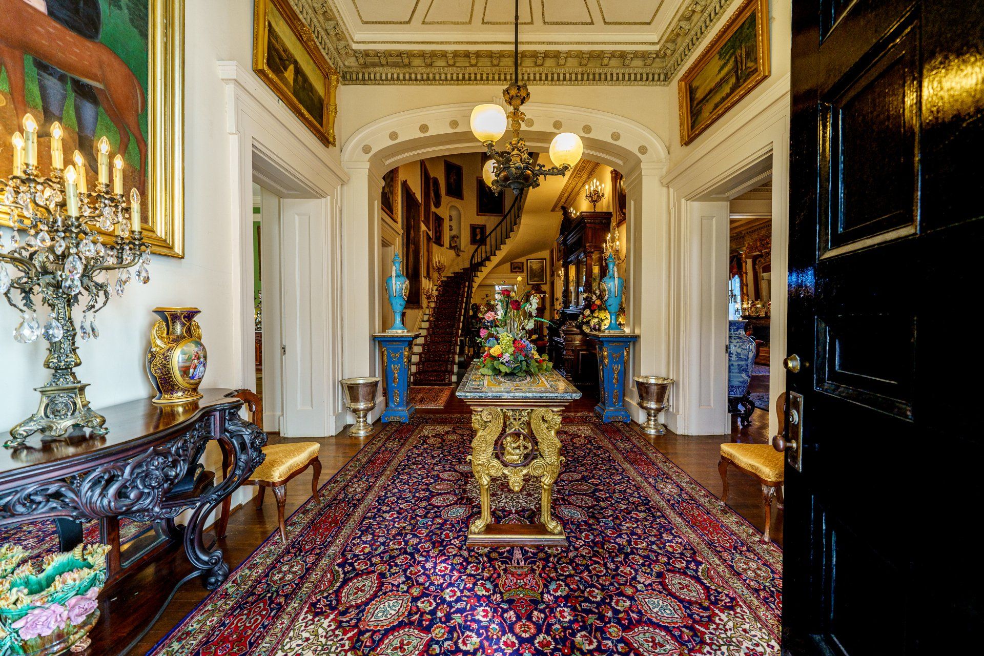 A hallway in a house with a table and a rug.