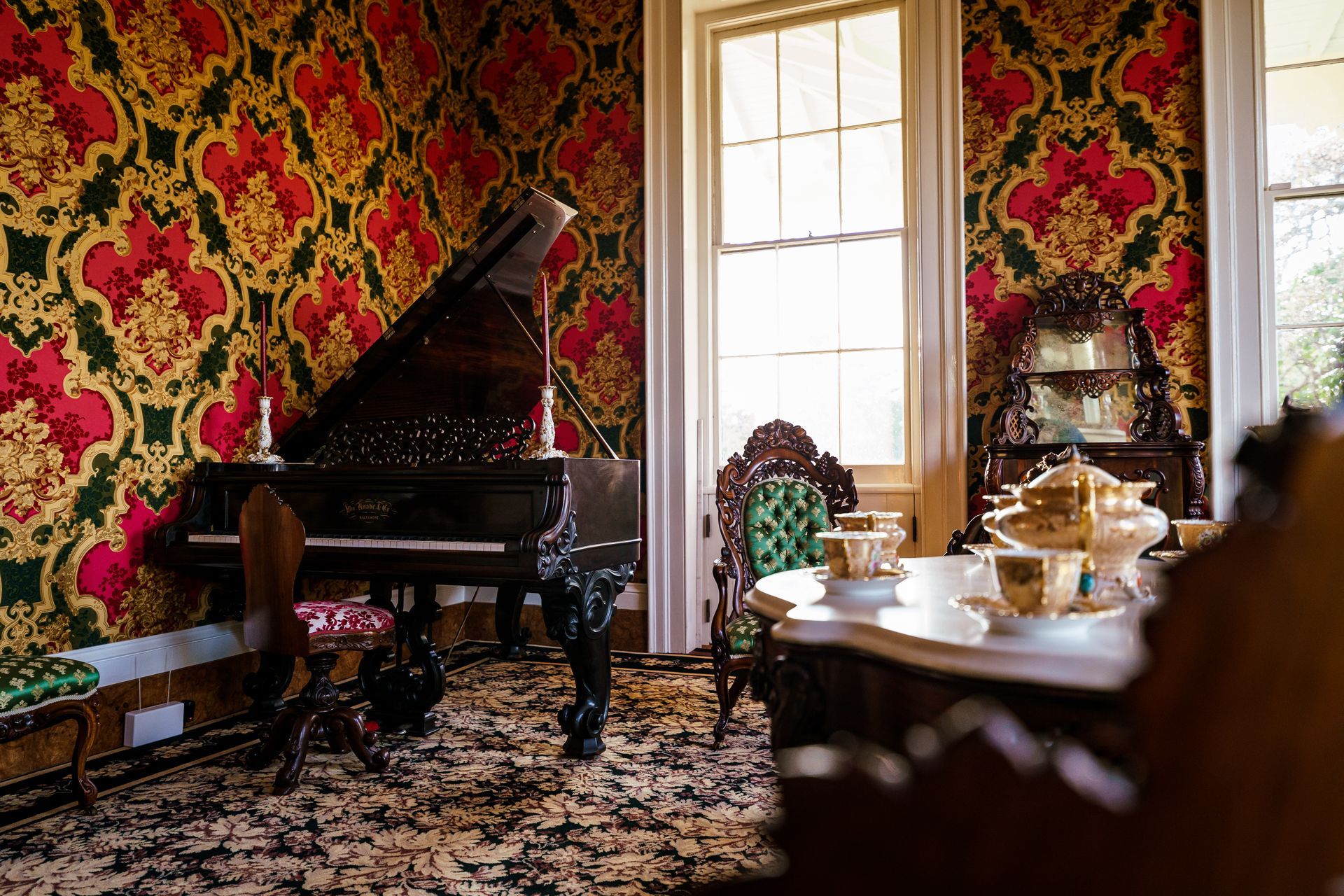 A living room with a piano , chairs , tables and a window.