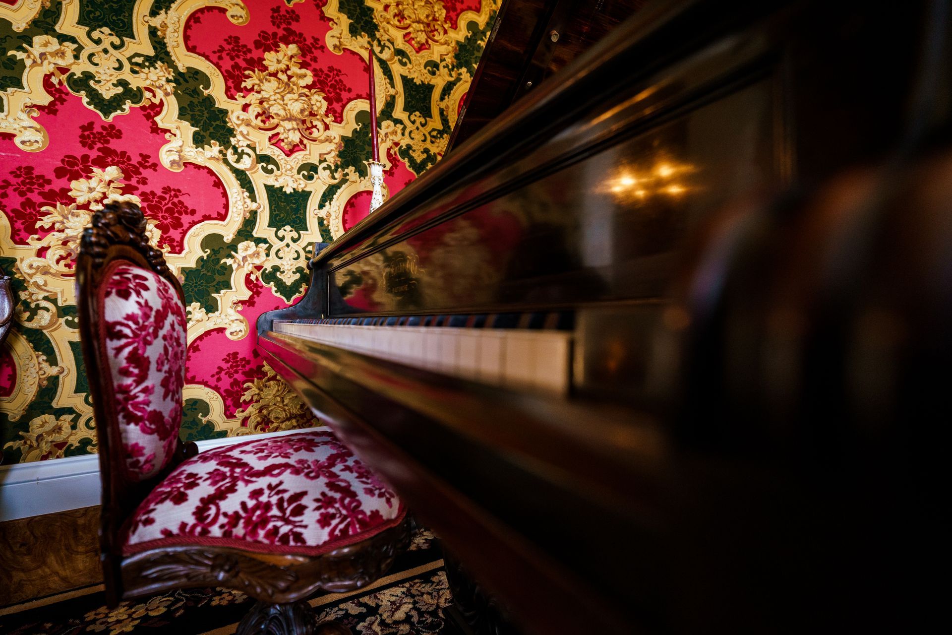 A chair is sitting in front of a piano in a room.