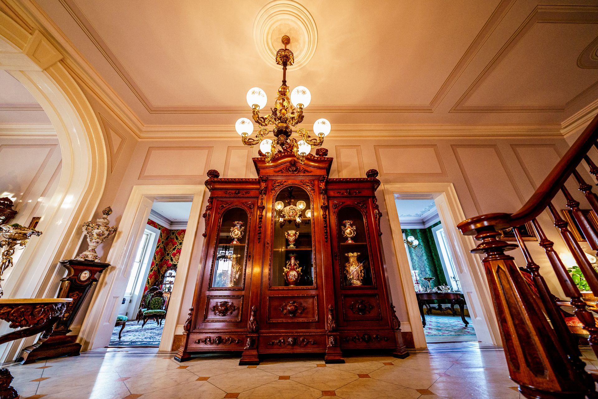 A large wooden cabinet with a chandelier hanging from the ceiling in a room.