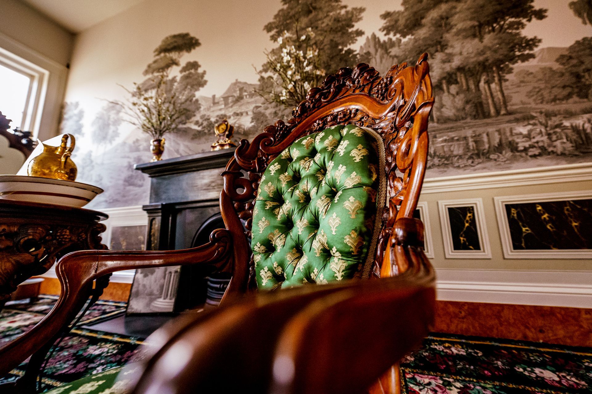 A wooden chair with a green cushion is sitting in a living room.