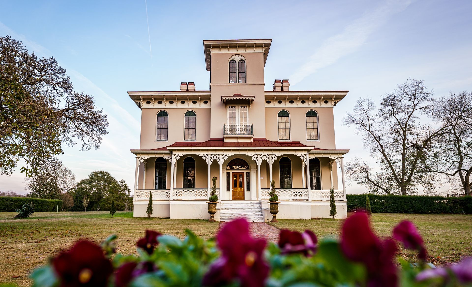 A large house with a porch and flowers in front of it.