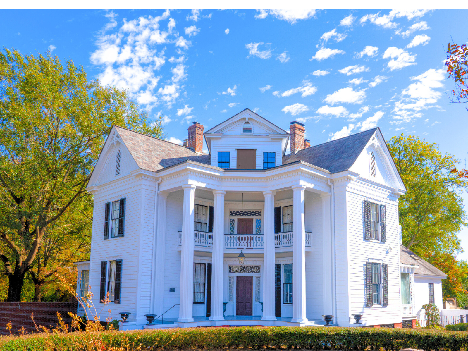 A large white house with columns and a blue sky in the background