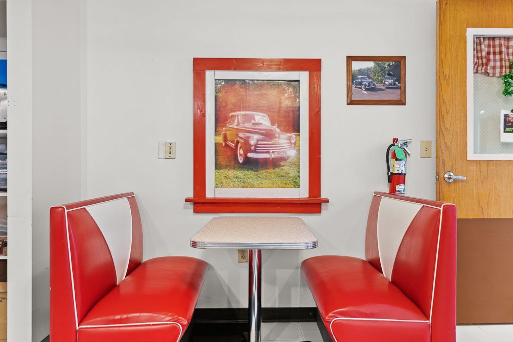 Red and white diner booth with vintage car photo on the wall, fire extinguisher.