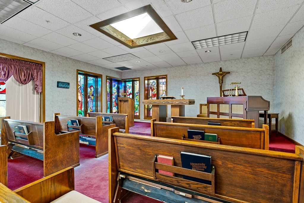 Interior of a church with wooden pews, stained glass windows, and a crucifix.