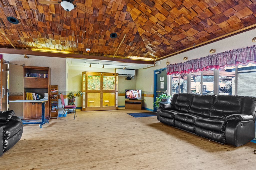 Interior of a room with a black leather sofa, brown ceiling, and a wooden screen.
