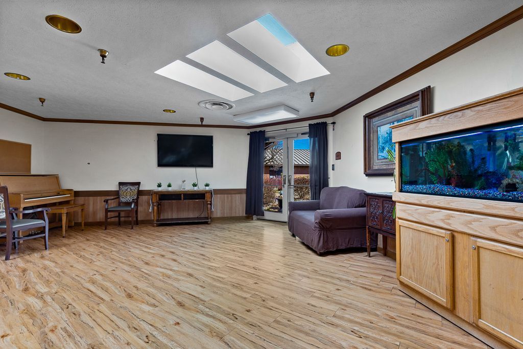 Spacious room with wood floor, large aquarium, skylight, and doorway leading outside.
