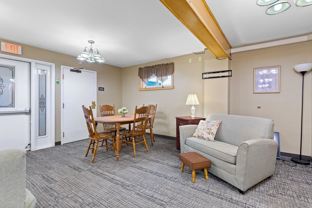 A common room with a round table and chairs, a couch, a lamp, and a rug.