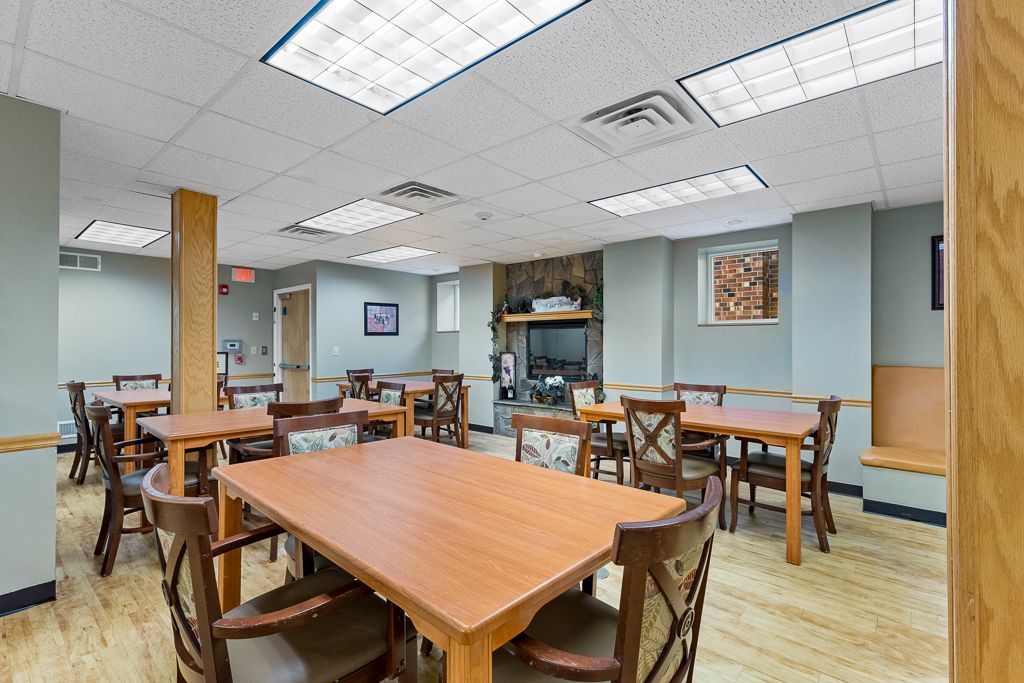 Dining room with tables, chairs, fireplace, and neutral-colored walls.