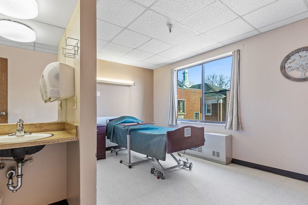 Hospital room: Bed near a window. Sink and mirror on the left. Neutral colors.