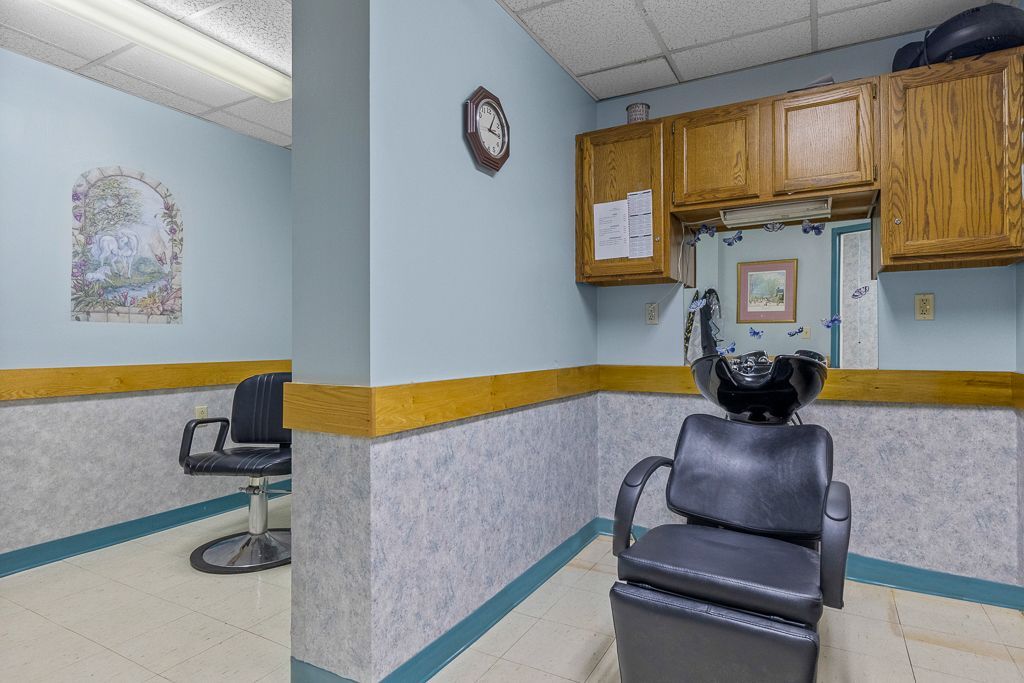 Hair salon interior: blue walls, styling chair, wash basin, cabinets, clock.