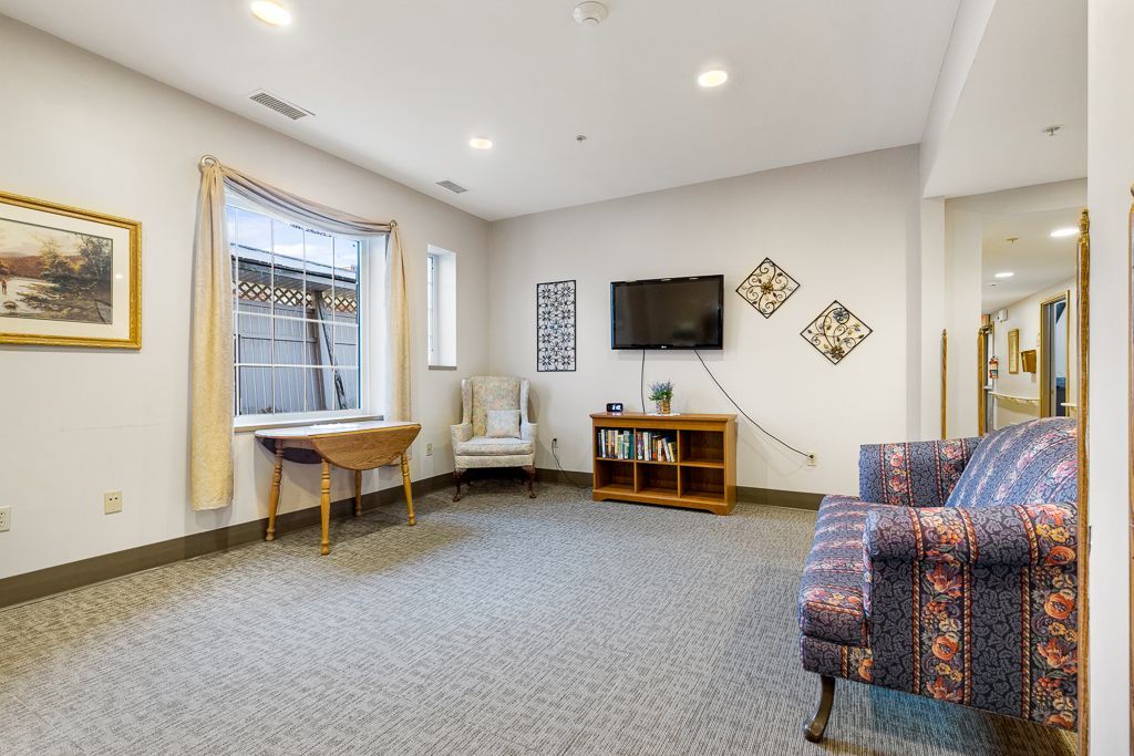 Living room with floral couch, window, TV, bookshelf, and chair.