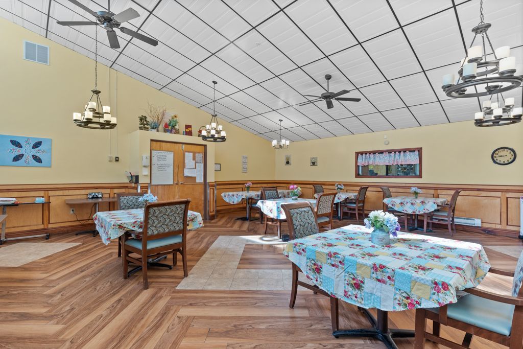Dining room with tables set for meals, chairs, and multiple chandeliers.