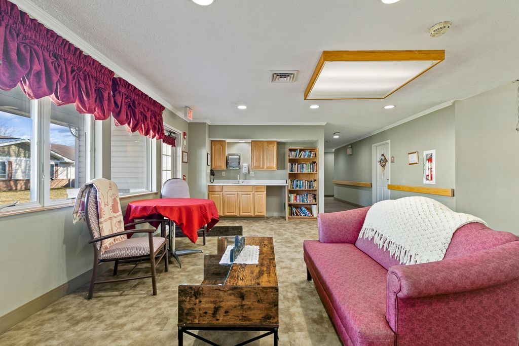 A brightly lit room with a sofa, table, and windows, suggesting a community space.