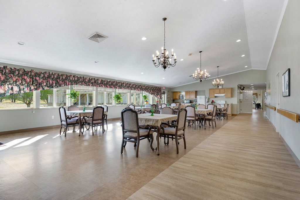Spacious dining hall with tables, chairs, chandeliers, and large windows with a view.