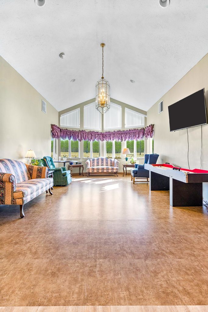 Long, light-filled room with multiple seating areas, a pool table, and a large TV.