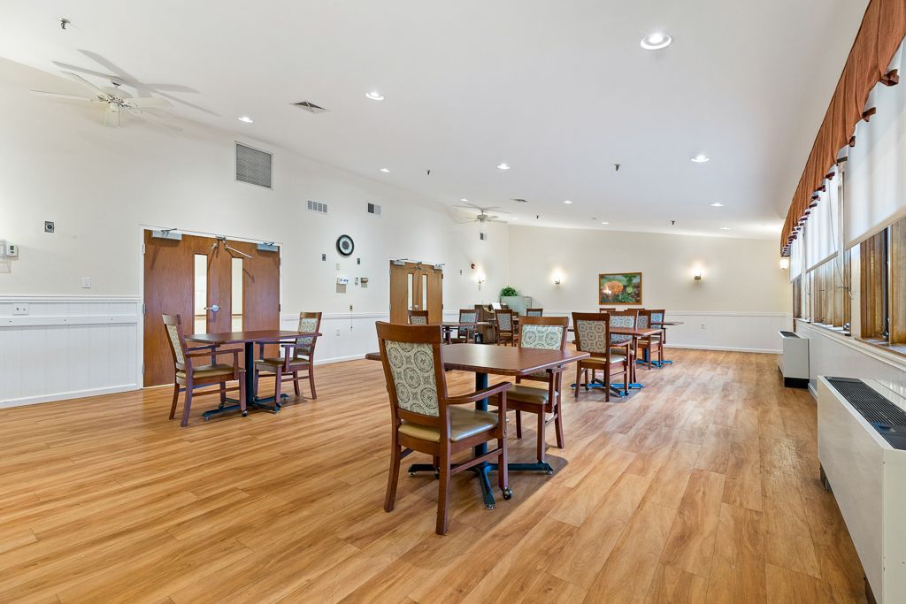 Empty dining room with wood tables and chairs, wood floors, and neutral walls.