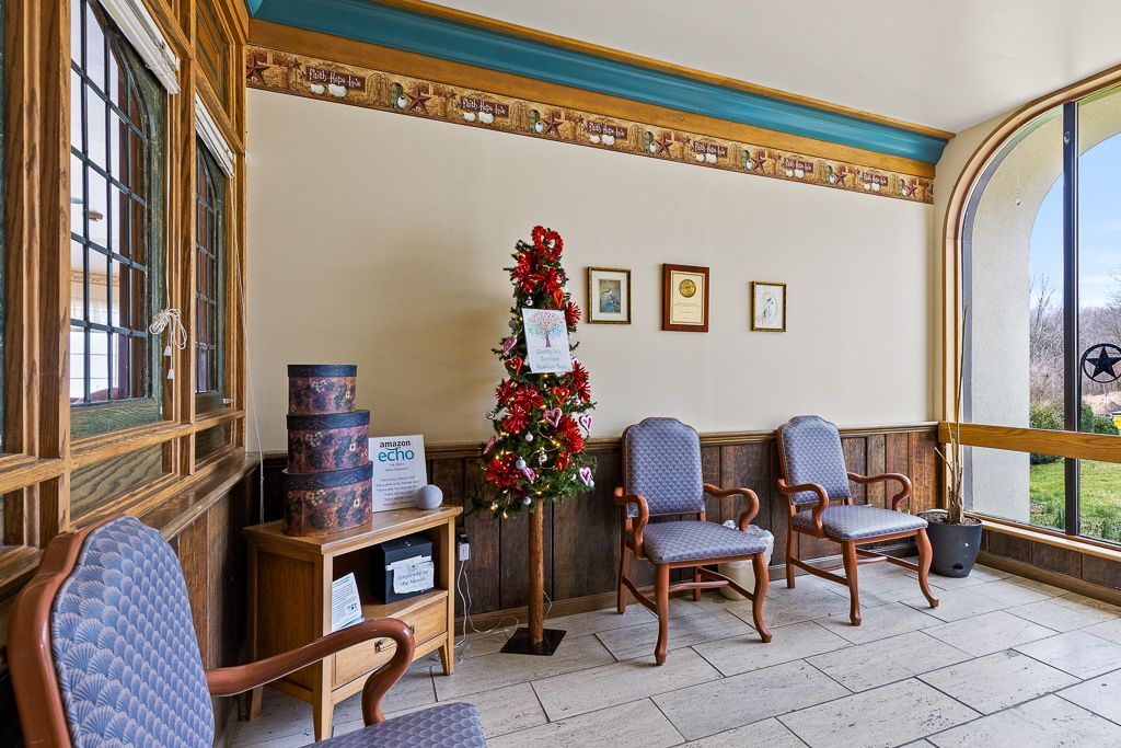 Waiting area with chairs, small table, festive decorations, and windows.