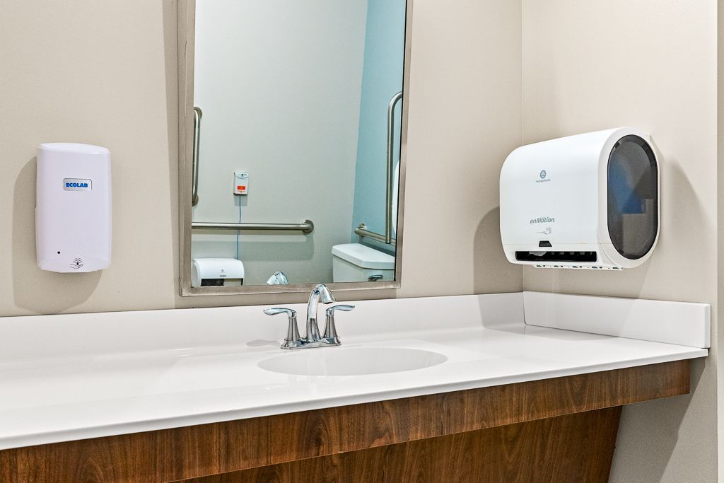 Bathroom with sink, mirror, soap dispenser, and paper towel dispenser.